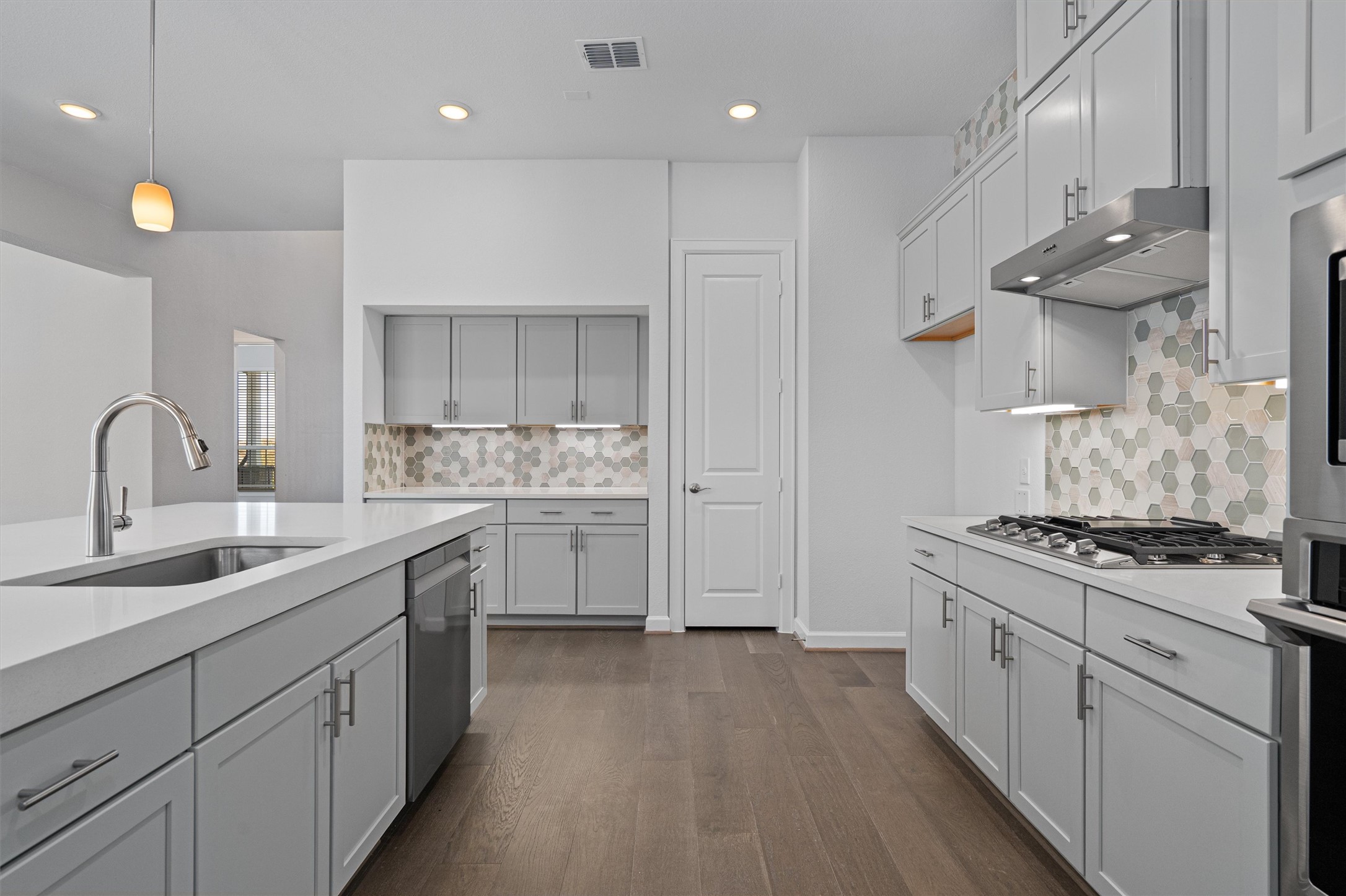 208 Lodestone Lane Austin, TX 78738 - Photo 11 of 38 Kitchen with pendant lighting, stainless steel appliances, dark wood-type flooring, backsplash, and light stone counters