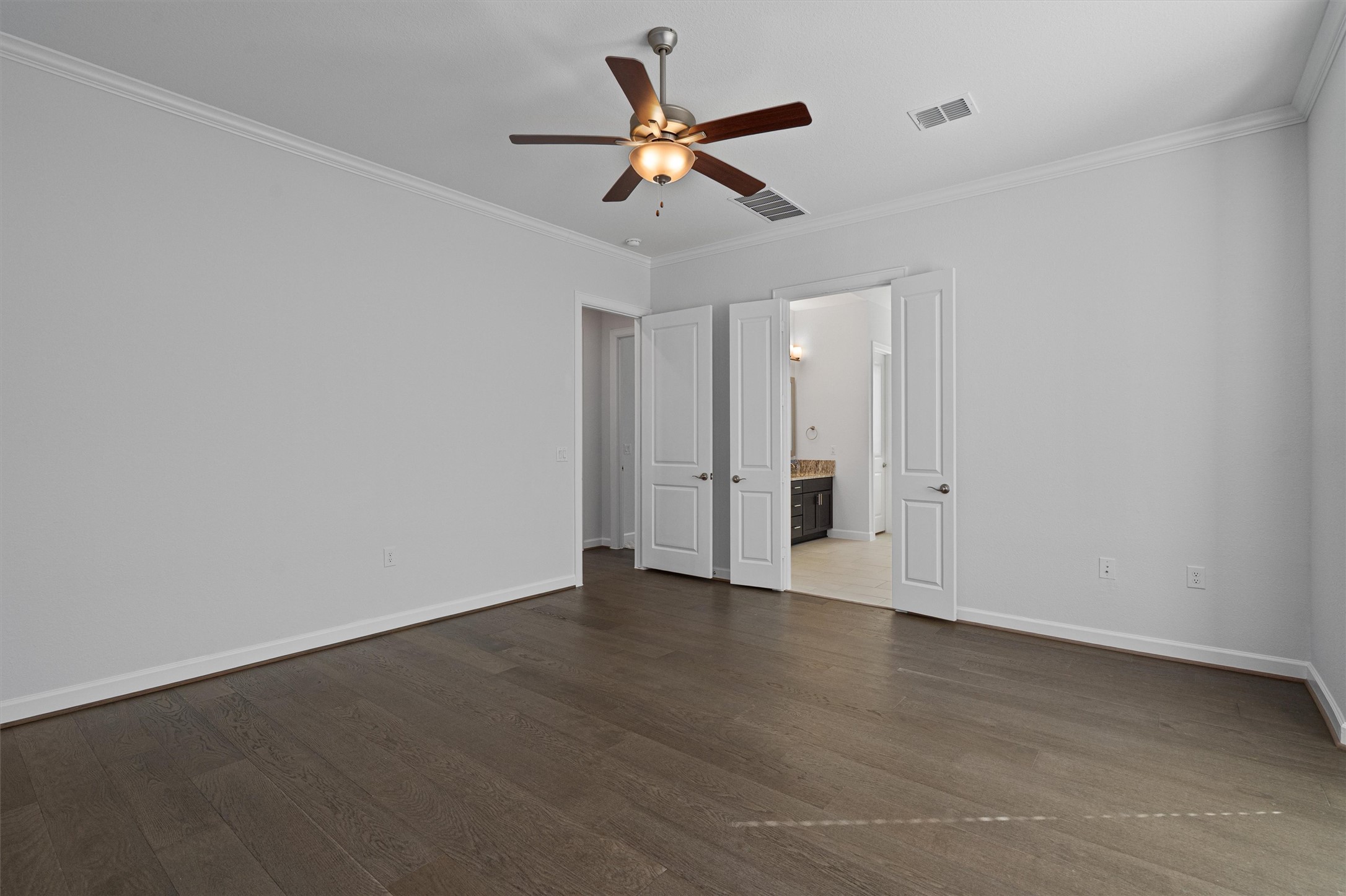 208 Lodestone Lane Austin, TX 78738 - Photo 13 of 38 Unfurnished bedroom featuring crown molding, ceiling fan, dark wood-style flooring, and ensuite bath