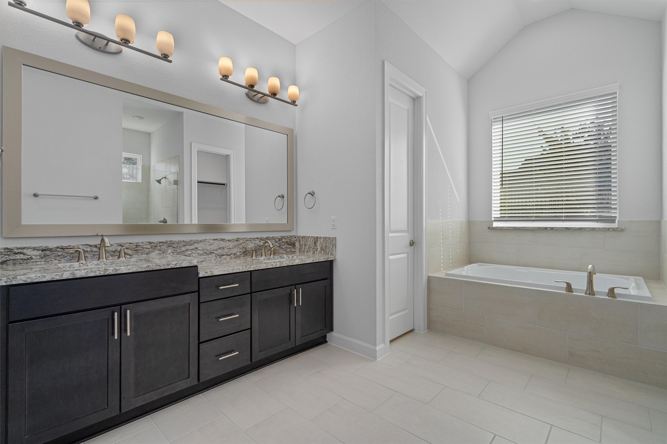 208 Lodestone Lane Austin, TX 78738 - Photo 14 of 38 Full bathroom with a bath, double vanity, a shower stall, light tile patterned floors, and vaulted ceiling