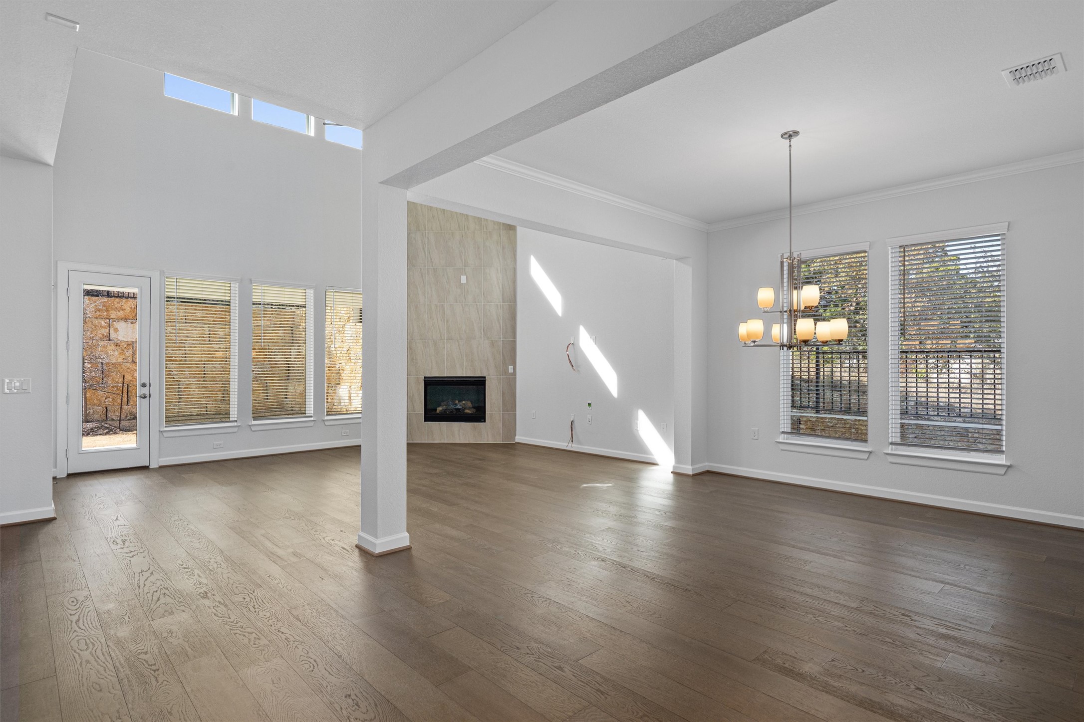 208 Lodestone Lane Austin, TX 78738 - Photo 7 of 38 Unfurnished living room featuring a fireplace, dark wood finished floors, a chandelier, and ornamental molding