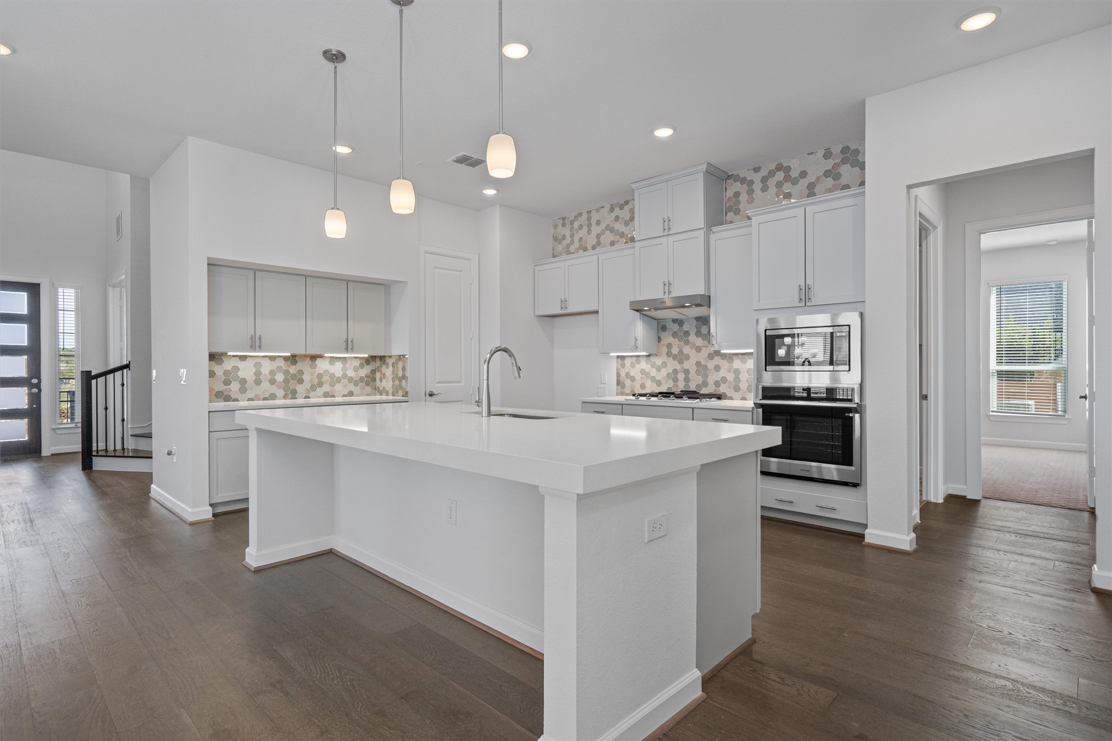 208 Lodestone Lane Austin, TX 78738 - Photo 10 of 38 Kitchen featuring healthy amount of natural light, decorative backsplash, dark wood-style floors, and an island with sink