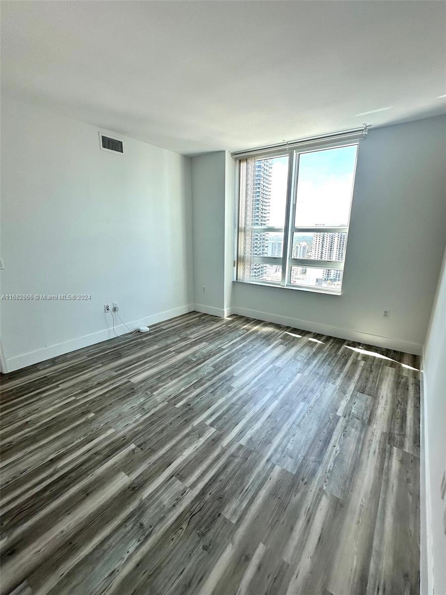 951 Brickell Avenue, Unit 3403 Miami, FL 33131 - Photo 17 of 26 a view of an empty room with wooden floor and a window
