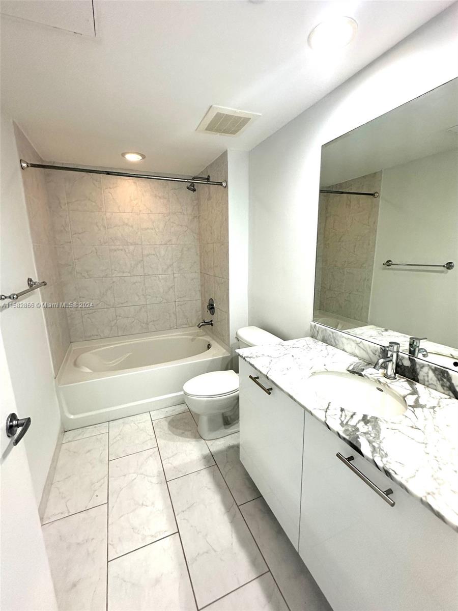 951 Brickell Avenue, Unit 3403 Miami, FL 33131 - Photo 18 of 26 a bathroom with a granite countertop sink a toilet a mirror and bathtub
