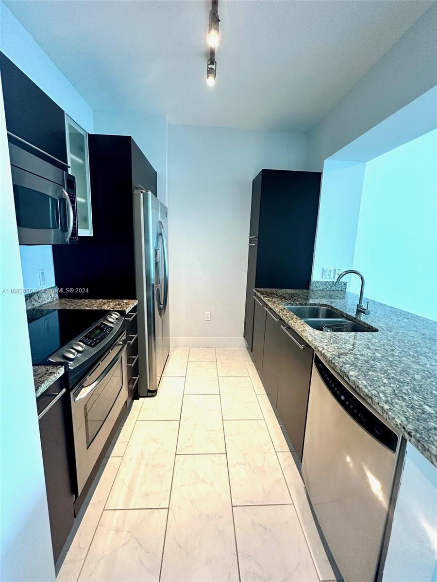 951 Brickell Avenue, Unit 3403 Miami, FL 33131 - Photo 21 of 26 a kitchen with granite countertop stainless steel appliances and wooden cabinets