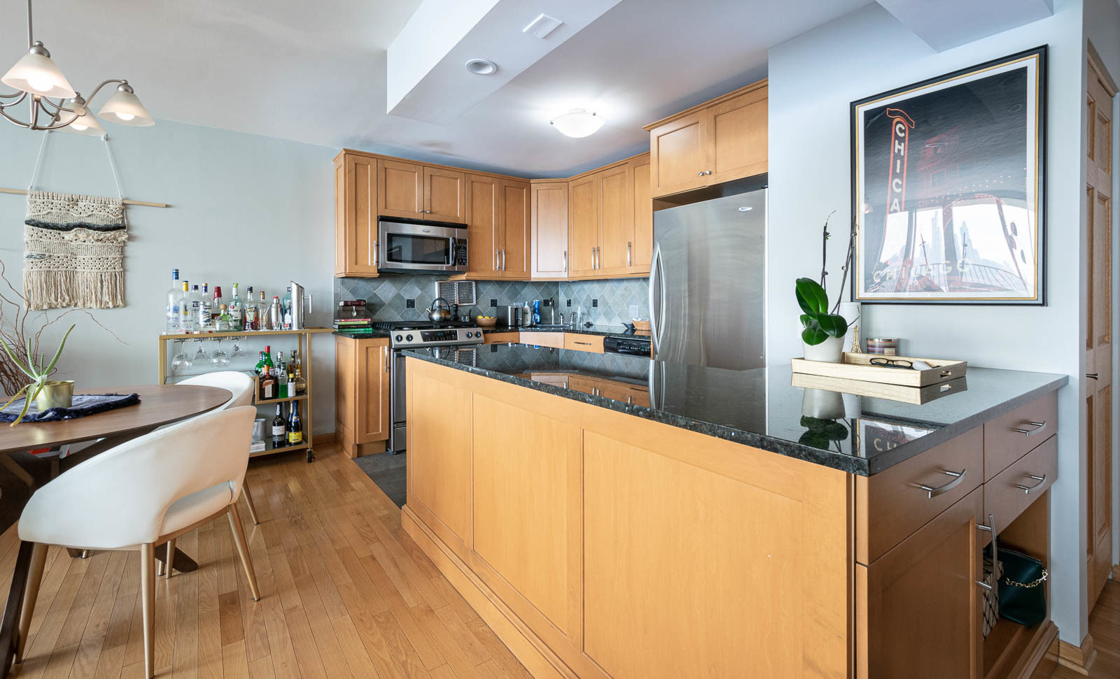 400 East Randolph Street, Unit 3405 Chicago, IL 60601 - Photo 6 of 17 a kitchen with stainless steel appliances granite countertop a refrigerator a sink dishwasher a stove and a dining table with wooden floor