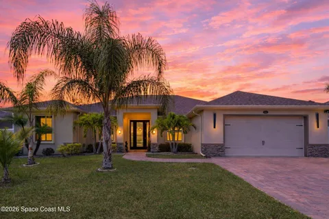 a view of a house with a yard and palm trees
