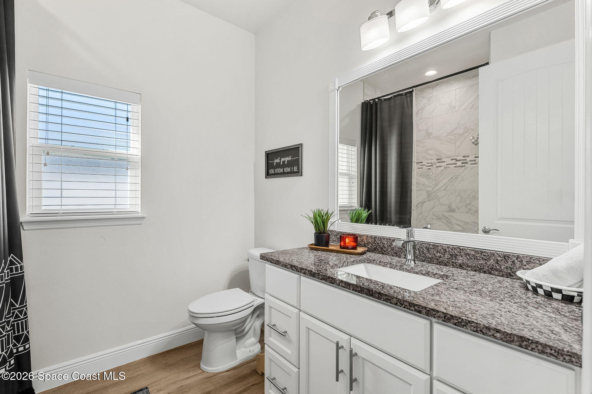840 Hawks Ridge Court Northeast Palm Bay, FL 32905 - Photo 21 of 41 a bathroom with a granite countertop sink toilet a large mirror and a window