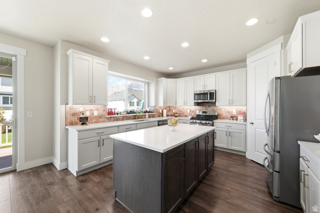 1434 West Stable Street Lindon, UT 84042 - Photo 15 of 76 Kitchen featuring stainless steel appliances, a center island, dark wood finished floors, backsplash, and two tone color scheme