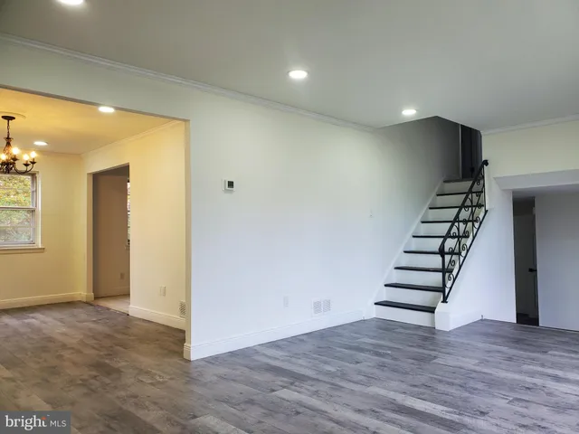 an empty room with wooden floor chandelier and windows