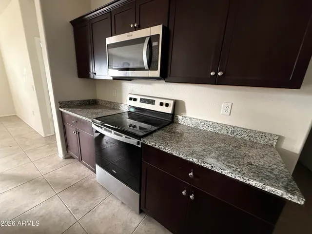 a kitchen with granite countertop cabinets stove top oven and microwave