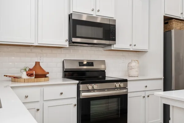a kitchen with white cabinets and stainless steel appliances
