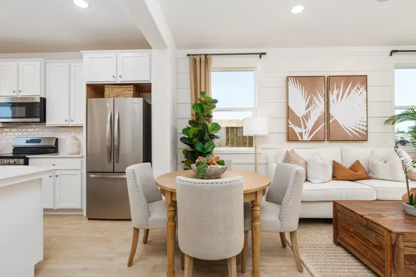 a dining room with furniture a kitchen view wooden floor and stainless steel appliances