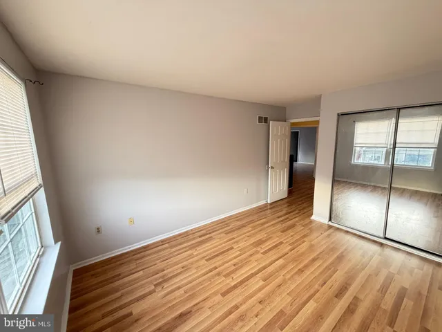 an empty room with wooden floor and windows