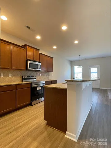 a kitchen with stainless steel appliances granite countertop a refrigerator a stove top oven a sink dishwasher and wooden cabinets