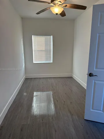 an empty room with wooden floor fan and window