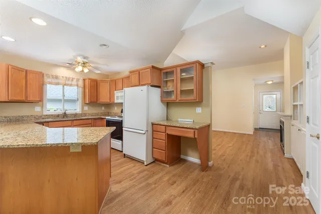 a kitchen with stainless steel appliances granite countertop a refrigerator a sink dishwasher a stove and white countertops with wooden floor