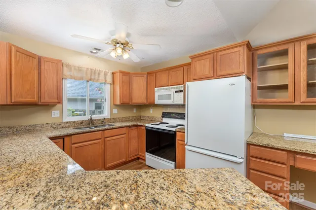 a kitchen with granite countertop a sink stainless steel appliances and cabinets