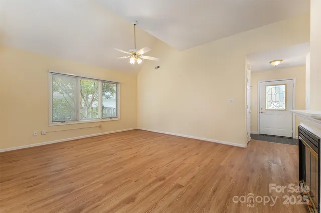 an empty room with wooden floor chandelier fan and windows