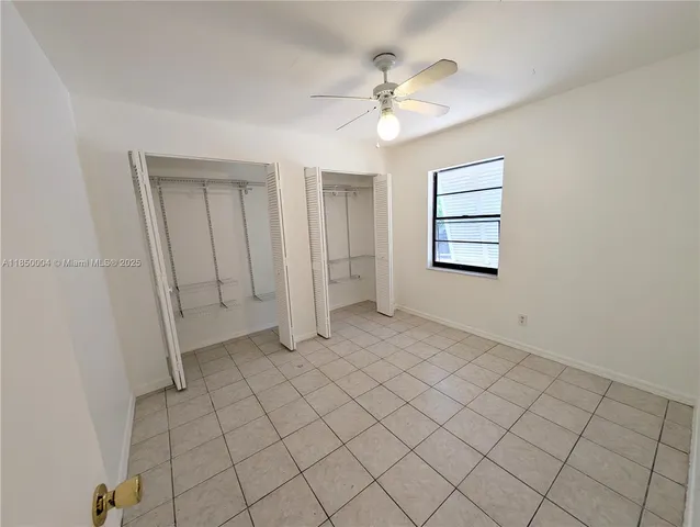 a view of an empty room with chandelier fan