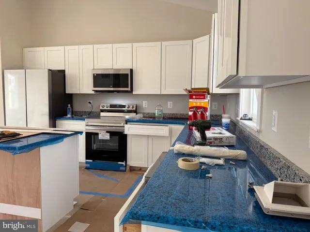 a kitchen with kitchen island granite countertop a stove a sink dishwasher and a refrigerator with wooden floor
