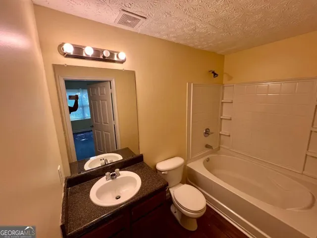 a bathroom with a granite countertop sink toilet mirror and bathtub