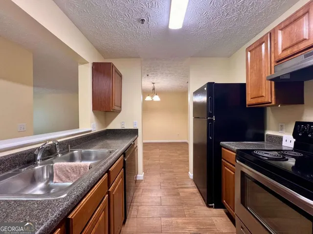 a kitchen with granite countertop a sink stove and cabinets