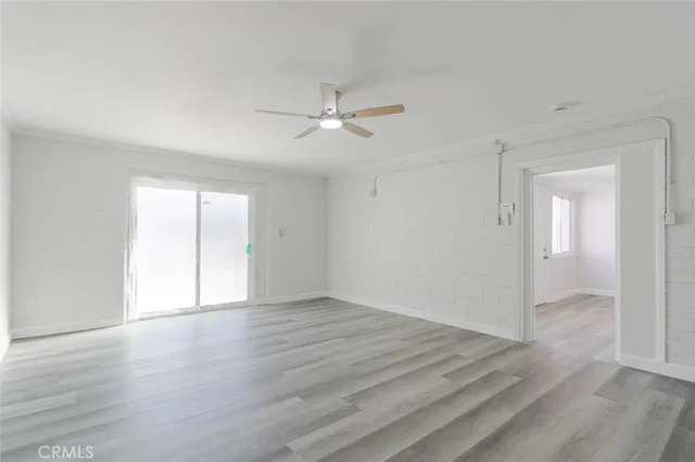 an empty room with wooden floor ceiling fan and windows