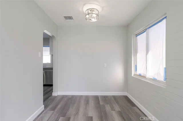 an empty room with wooden floor cabinet and windows