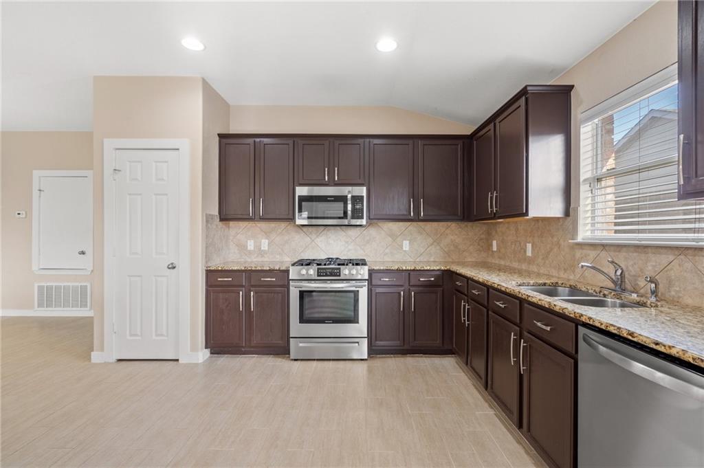 20224 Merlin Falcon Trail Pflugerville, TX 78660 - Photo 16 of 40 A well-appointed kitchen showcasing rich cabinetry, sleek stainless steel appliances, and gleaming granite countertops.