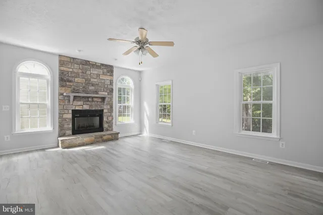 an empty room with windows fireplace and a sink