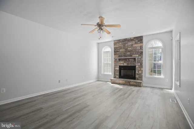 an empty room with wooden floor fireplace and windows