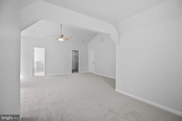 a view of an empty room with a chandelier fan