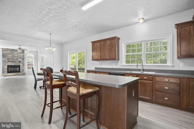 a open kitchen with stainless steel appliances granite countertop a stove a sink dishwasher a dining table and chairs with wooden floor