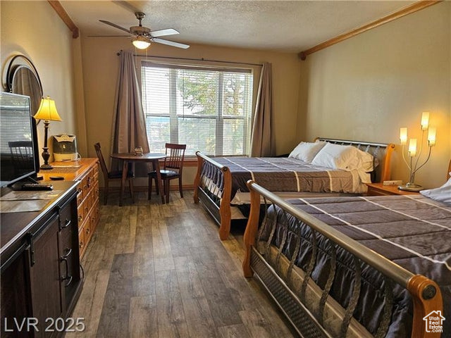 223 Hunter Ridge Drive, Unit E121 Brian Head, UT 84719 - Photo 16 of 35 Bedroom with dark wood finished floors, crown molding, and a textured ceiling
