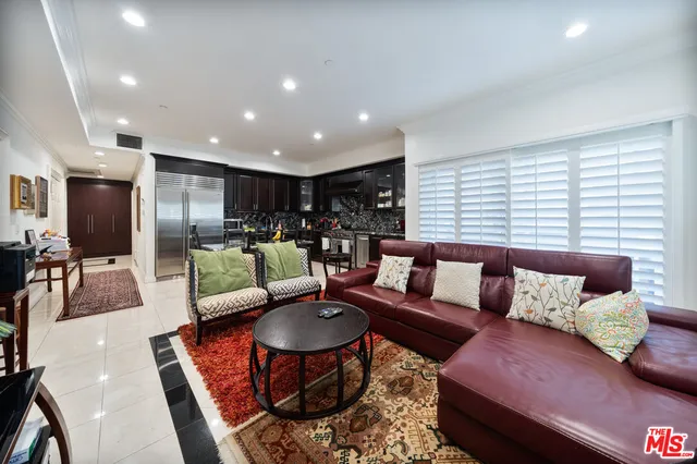 a living room with furniture kitchen view and a large window