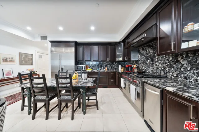 a kitchen with stainless steel appliances granite countertop a stove top oven a sink a dining table and chairs