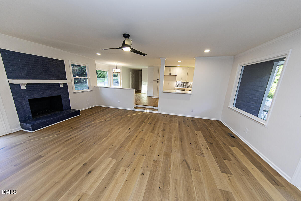 1208 Lorimer Road Raleigh, NC 27606 - Photo 10 of 37 an empty room with wooden floor fireplace and windows
