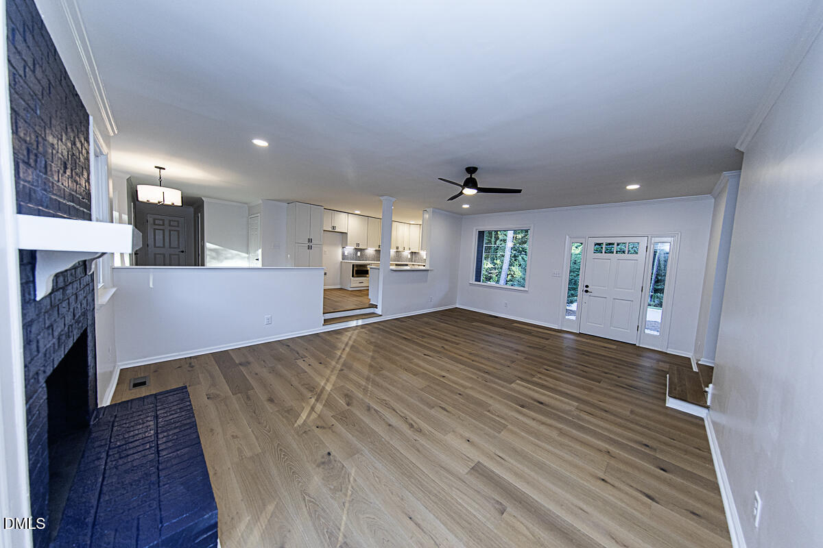 1208 Lorimer Road Raleigh, NC 27606 - Photo 7 of 37 an empty room with wooden floor and fireplace