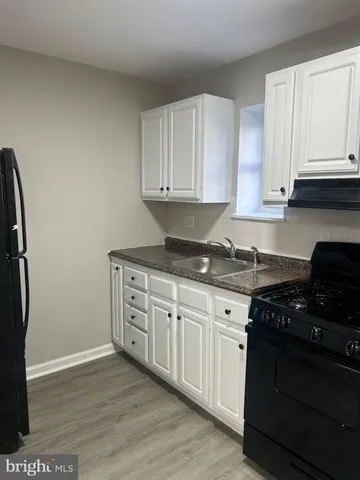 a kitchen with granite countertop white cabinets and black appliances