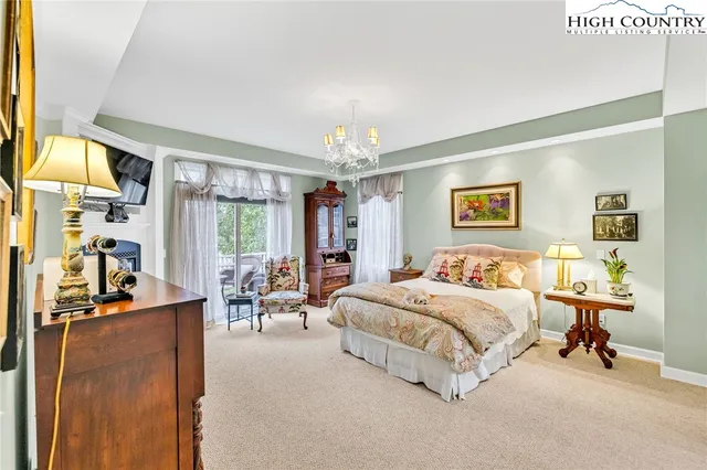 a bedroom with a bed couch chandelier and a window