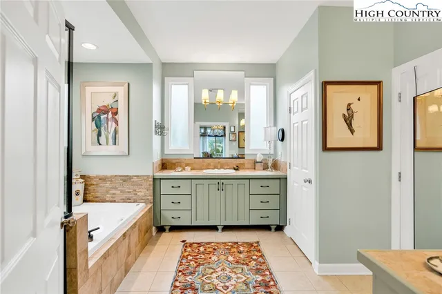 a bathroom with a granite countertop sink a mirror a vanity and a bathtub