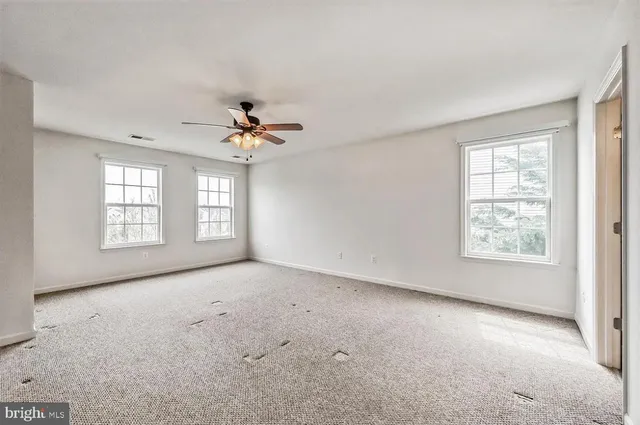 an empty room with windows and chandelier fan