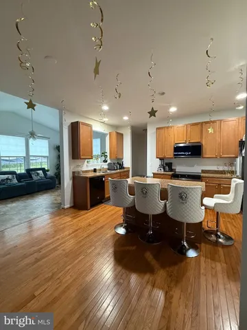 a living room with stainless steel appliances kitchen island granite countertop a table chairs sink and cabinets