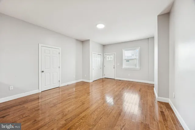 a view of an empty room with wooden floor and closet