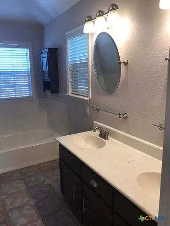 a bathroom with a sink vanity tub and a mirror