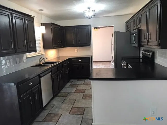 a kitchen with stainless steel appliances granite countertop a refrigerator a sink and wooden cabinets