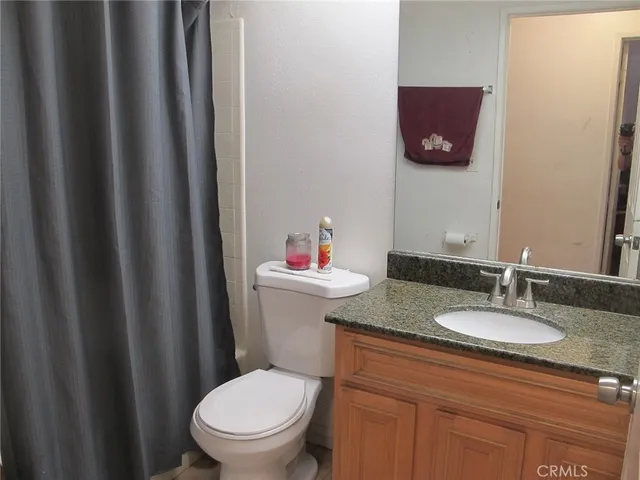 a bathroom with a granite countertop toilet and a sink