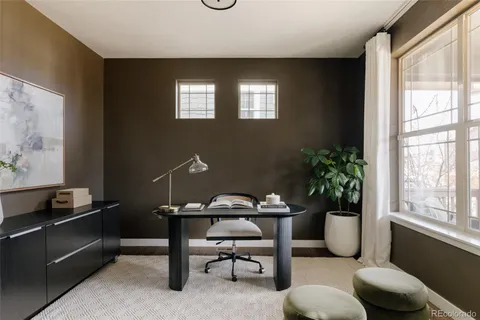 a view of a workspace room with furniture and a window