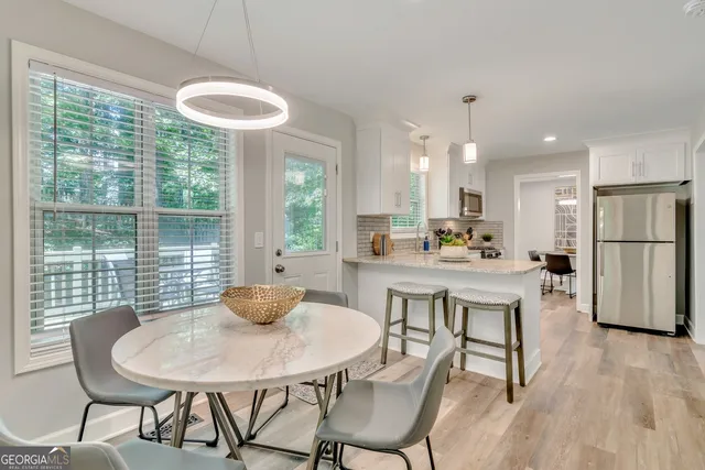 a kitchen with stainless steel appliances granite countertop a table chairs and a refrigerator