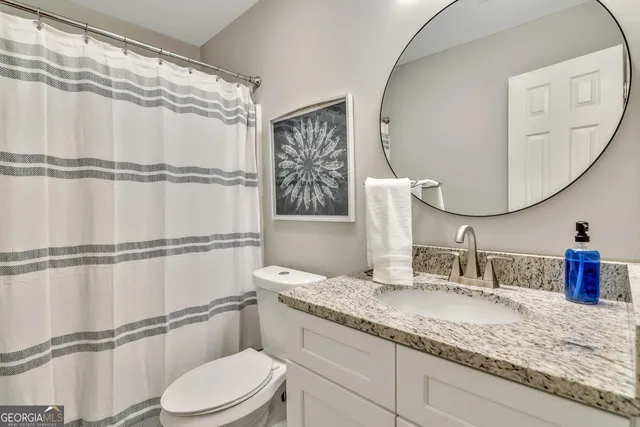 a bathroom with a granite countertop sink mirror vanity and toilet